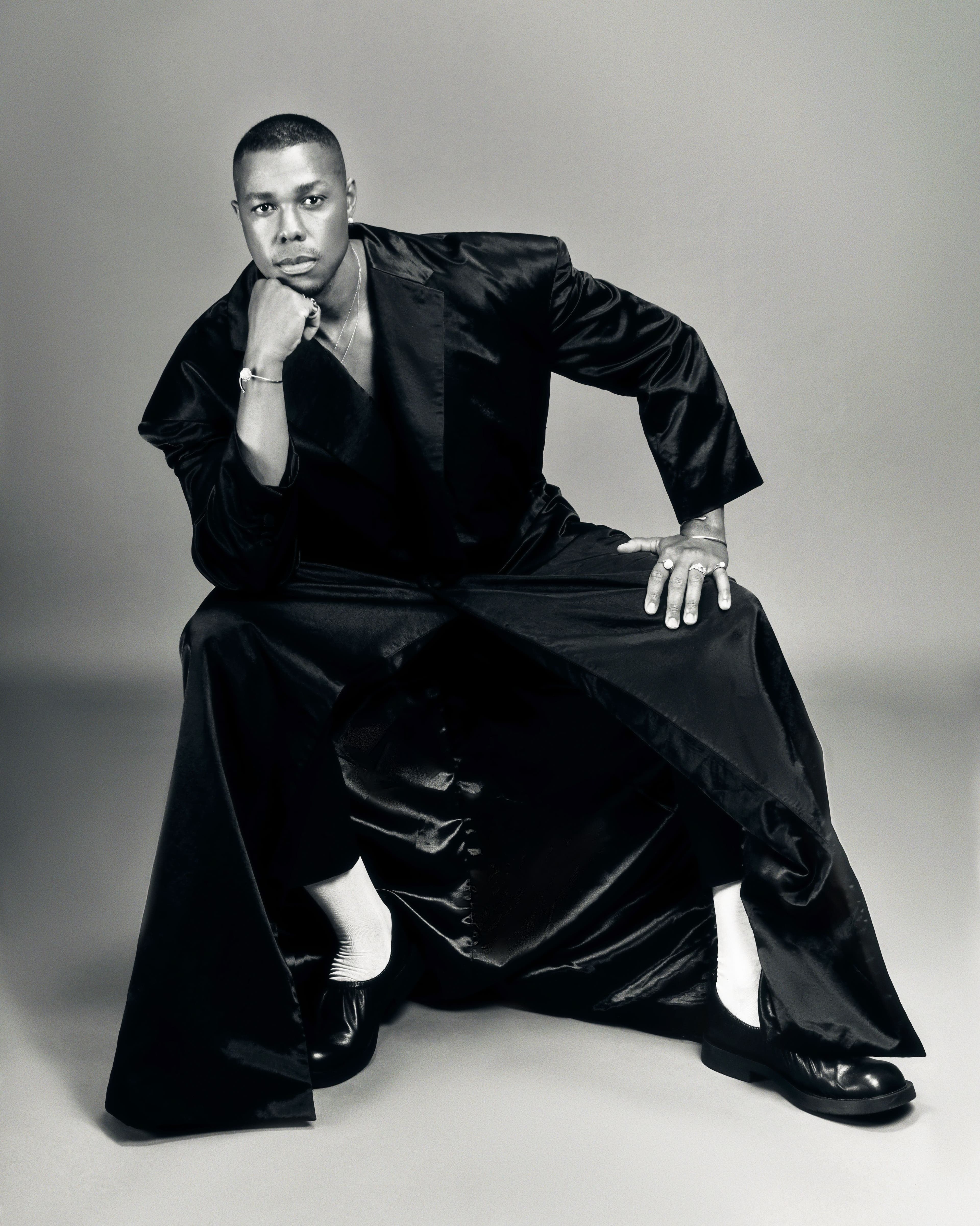 COAT by ,Willy Chavarria,. PANTS by ,Yohji Yamamoto,. SHOES by ,CAMPERLAB,. NECKLACE and RINGS by ,Miansai,. RING by ,Bernard James,.