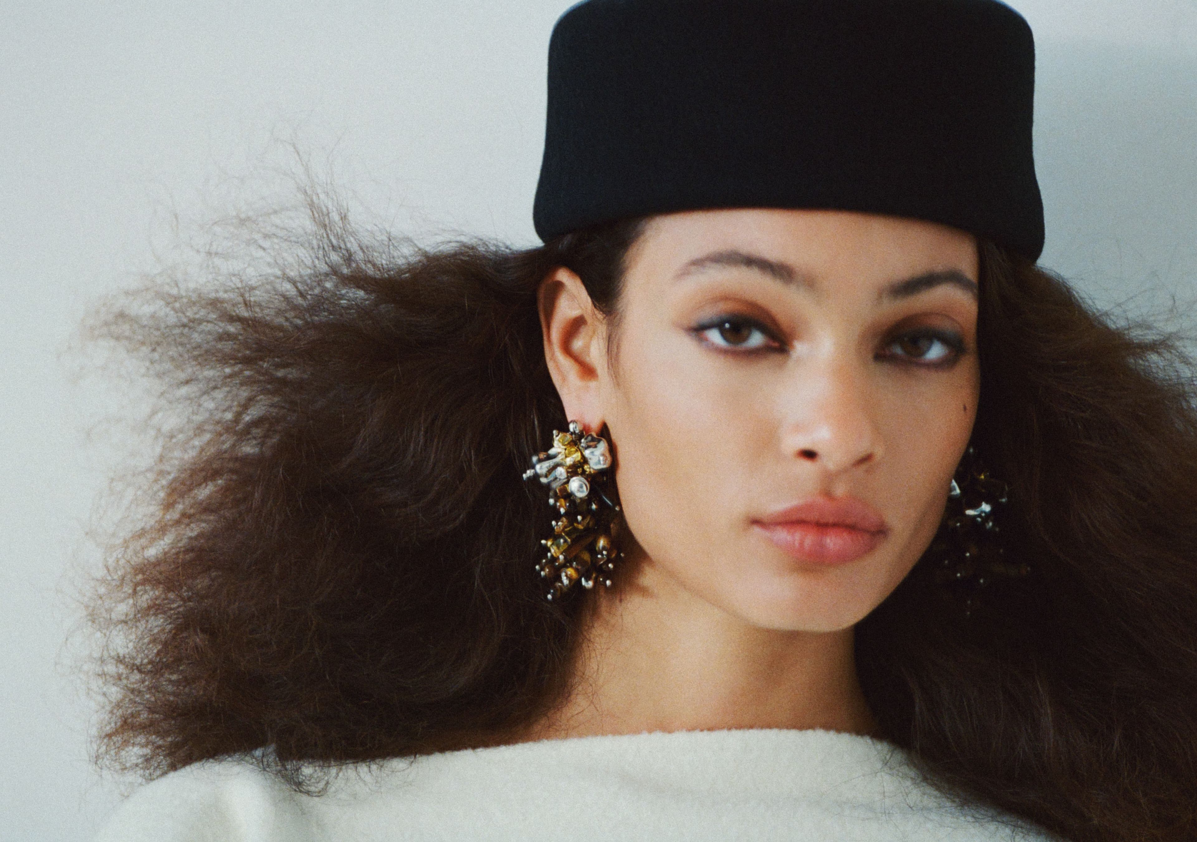 TOP by Toteme; HAT by Gigi Burris; EARRINGS by Dries Van Noten