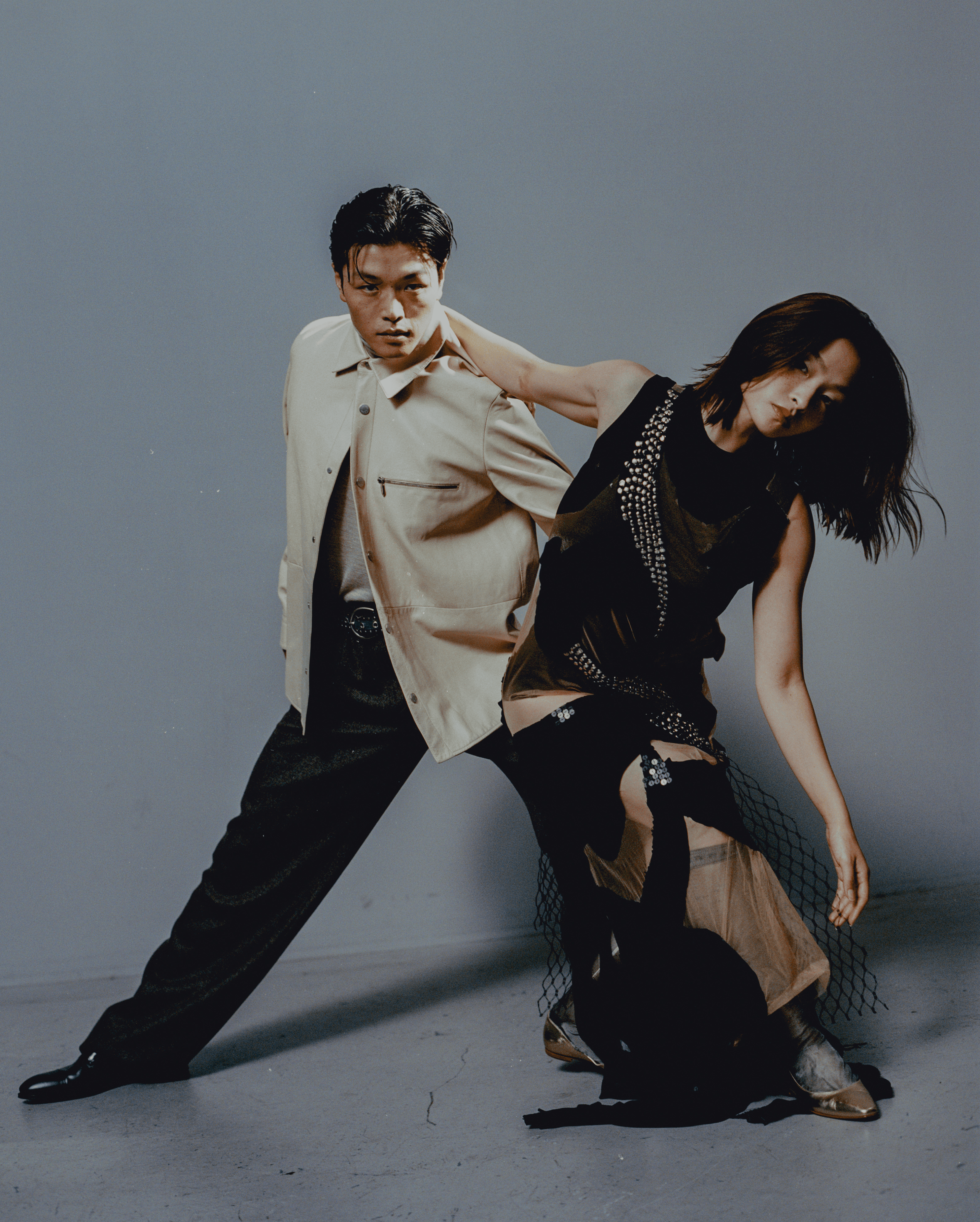 Alex wears all CLOTHING by Hermès. BELT, stylist’s own. SHOES by Louis Vuitton. RING by The Great Frog. Maia wears DRESS by Malcolm D. Costa. TOP by Issey Miyake. SOCKS by Marni. SHOES by Manolo Blahnik.